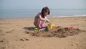 Jeune fille construisant un château de sable sur la plage d’été