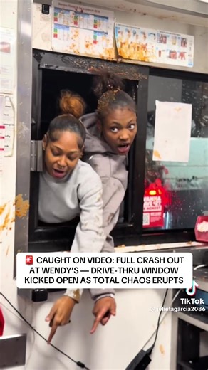 🚨 CAUGHT ON VIDEO: FULL CRASH OUT AT WENDY’S — DRIVE-THRU WINDOW KICKED OPEN AS TOTAL CHAOS ERUPTS What starts as a dispute over a few dollars at the drive-thru speaker quickly spirals into something way bigger. Multiple women jump out of their car, march up to the window, and kick it open. Within seconds, they’re leaning halfway inside, screaming, cursing, and launching drinks, ice, and condiments at the employees. It’s not just yelling... it’s a full physical breach of the window with food an
