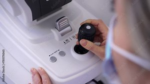 Optometrist female using the equipment joystick of generic eye scanner machine