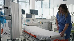 Nurse preparing examination table in emergency room, examination room. Discarding of used paper and rolling out the fresh sheet of paper for next patient.