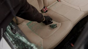 A wallet left on the beige leather back seat is stolen through a broken window, capturing the aftermath of a reckless theft. The scene depicts the brazen act with vivid clarity