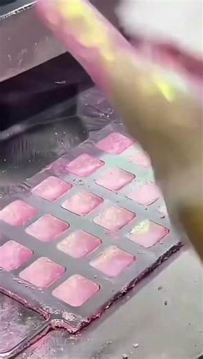 Filling small square molds with mixed eyeshadow powder to create colorful palettes easily today!