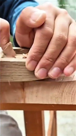 using a small manual hand plane to smooth and shape the curved edge of a wooden table surface