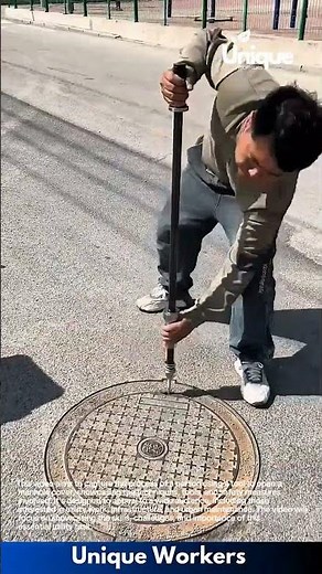 Manhole opening: person using a tool to open a manhole cover