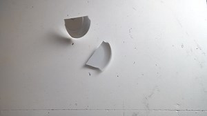 Premium stock video - Smashing plate into pieces on a dirty floor, slow motion top down shot