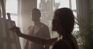 Female artist drawing sketch of nude male model