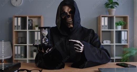 Sinister figure wearing dark hooded cloak and skull mask holding hourglass while pointing with skeletal finger at time. Grim reaper of death reminding of passing time and inevitable end of life.