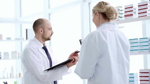 two pharmacists compiling a checklist of medications.