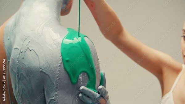 Colourful paint flowing over the man body close-up. Body art therapy with many various of paints. Painting on human body.