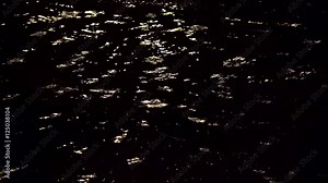 Heavy rain in a puddle on an urban sidewalk at night with a light reflection.