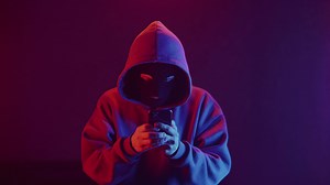 phone scammer in a mask writes a text message