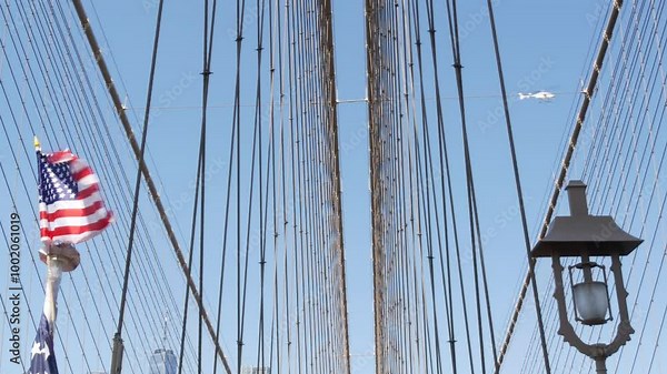 American flag on Brooklyn Bridge to Manhattan, New York City. Patriotic symbol of liberty, freedom, democracy and independence, bridge cables. United States star-spangled banner in wind. Travel USA.