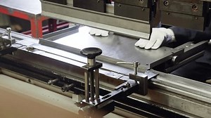 Bending machine operator bends sheet metal product. Employee works at metal factory. Bending sheet metal on hydraulic machine. Close-up in 4K, UHD