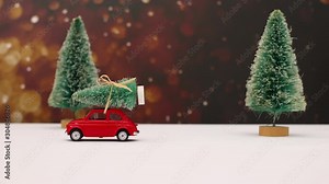 Stop motion animation of little red car passing and drives Christmas tree on the roof c