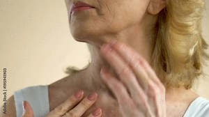 Middle-aged woman carefully examining wrinkled skin of her neck and chest
