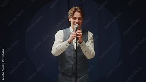 StandUp cafe, comedy concert. Man telling jokes on stage. Male comedian speaks with audience using microphone, humorous monologue. Mentor coach training. Public speaking masterclass.