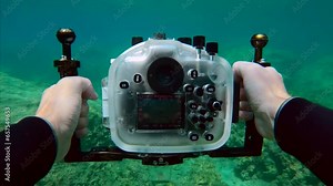 POV underwater shot, Cameraman swims underwater holding camera housing in his hands and films video swimming over rocky bottom. First person view underwater, Mediterranean sea