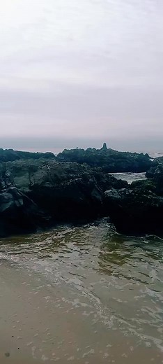 Serene Beach Scene With Waves and Rocky Formations