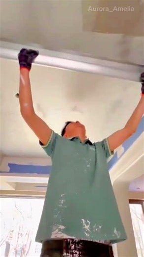 smoothing a white ceiling with a long metal scraper to create a flat finish during home renovation
