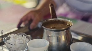 A woman presents traditional Turkish and Bosnian coffee, served in a pot with cups and sugar on a tray. It embodies hospitality and culture, offering aromatic refreshment with authentic flavors.