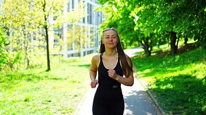 Young woman runner training in summer park. Close up fitness woman jogging outdoor. Morning running concept. High quality 4k footage