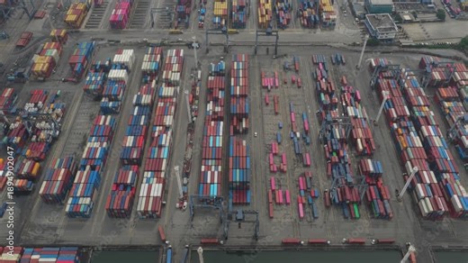 Vertical aerial view of container stacks at a busy seaport in Jakarta, Indonesia, highlighting dense logistics operations and industrial port layout.