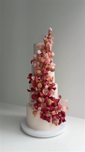 K CAKE on Instagram: "Layers of warmth, depth, and movement—this four-tier wedding cake captures the essence of autumn with cascading gum paste petals in rich seasonal hues. Elevated with acrylic separators, each tier floats effortlessly, letting the colors flow like falling leaves. A bold, textural statement for a celebration wrapped in warmth"