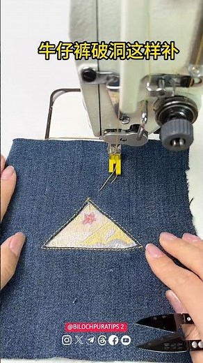 A sewing machine applying a decorative patch to a piece of denim fabric. Triangular patch
