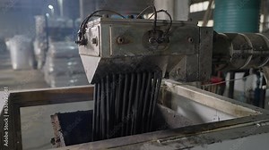 Industrial machine deals with the plastic extrusion process at the plant. Modern plastic extrusion machine with lots of molten material strings. Machine extruding the recycled plastic waste.