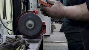 worker grinds a brake pad on a grinding machine