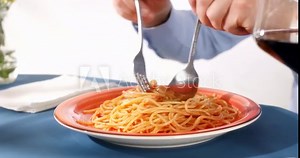 spaghetti eating. spaghetti rolled on a fork with a spoon. close-up. italian food. sunny day.