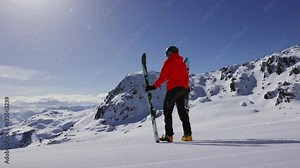 Slow motion of skier looking at mountains. 4K skiing footage, one man skier staying on ski slope on sunny winter vacation day with clear blue sky in European alps mountains, Austria.