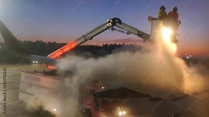 Aircraft De-Icing by Airport Ground Crew in De-Icing Truck at Dawn