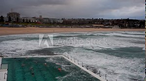 bondi icebergs and a people swimming and wild waves crashing inside the pool , sydney australia 8 , 30 , 2019