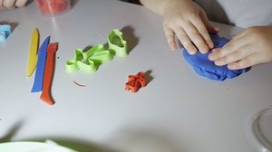 Hands Child in Process of Modeling of Plasticine at Table in Nursery Room. Child Kid Boy Playing Colorful Clay Toy at Playroom of Home.