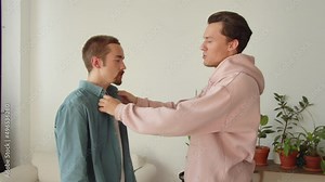 During entertaining conversation, standing together, two young lgbt men are fixing each others clothes Stock Video