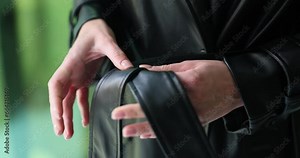 Woman ties long belt of elegant leather coat. Stylish clothing design for every day