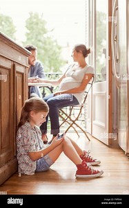 Girl engrossed in video game while parents chat in background Stock Photo - Alamy