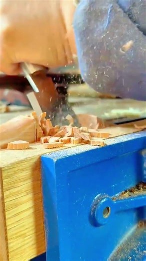chipping away wood using a sharp metal chisel to create a deep rectangular hole for joinery purpose