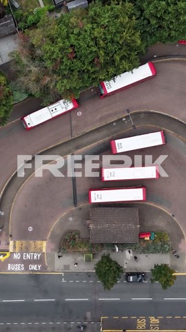 Vertical top-down timelapse over bus station showing buses, trains, and cars arriving and departing, with the bus depot, train station, and car park all visible in one busy urban transport hub scene | Premium Stock Video Footage
