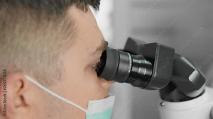 A dentist uses a dental microscope to perform precise and reliable dental procedures, helping himself with a microscope, performing precise processing and placement of dental implants.