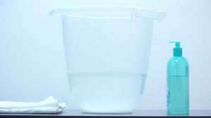 Parent hands introducing newborn in tummy tub, parent bathing little child, warm