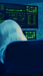 A young man is watching several monitors with code patterns - Free Stock Video