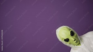 A funny green alien in a white suit peeks out of the corner of the frame against a purple background. Alien invasion