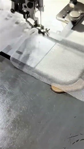 sewing a white net fabric using professional white sewing machine on a grey table in an indoor area