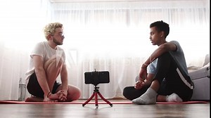 Two men talking on the floor and filming video