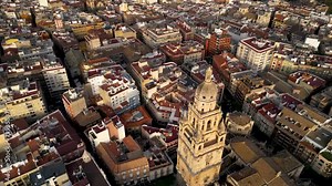 Cinematic aerial view of Murcia Cathedral and city center. Drone backwards starting from Cathedral tower and tilt up camera revealing all the city center. Rooftops of Murcia. Travel destination.
