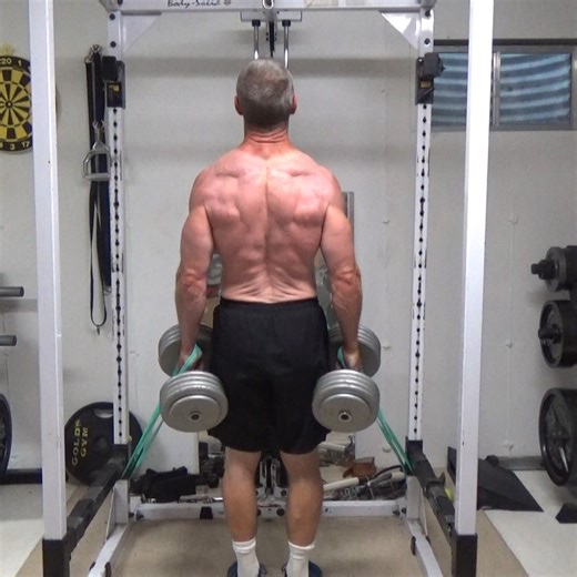 Nick Nilsson on Instagram: "Band-Dumbbell Mid-Trap Shrugs... this setup uses bands and dumbbells to put directional resistance on the middle traps and upper traps. You'll need a couple of small/medium bands for this. I've got them looped in half around the uprights of the power rack with the rails set low. This is the easiest place to attach them. If you're in a busy gym, any pair of solid objects (or Smith machine uprights) about 5 feet apart will work. It is important to note, you're not going
