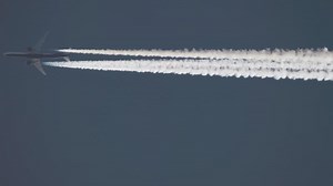 Download Airplane contrail in clear blue sky. Aircraft flying overhead, long shot for free