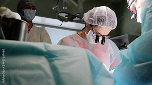 Surgical team conducts operation modern medical techniques doctors assistants hospital setting. Surgeons with team perform surgical procedure advanced medical technology successful surgeries.